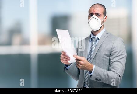 Worried masked businessman holding a document during coronavirus pandemic Stock Photo