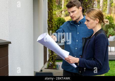 young couple looking at blueprints of house they want to buy Stock Photo