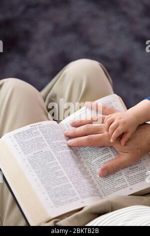 Grandad reading stories from the Holy Bible to his young grandson Stock Photo