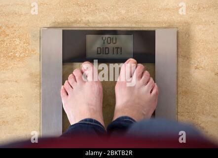 Woman is successful in her fitness and scale she is standing on says you did it Stock Photo