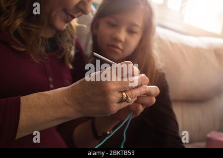 Loving Grandmother teaches her little granddaughter how to knit Stock Photo