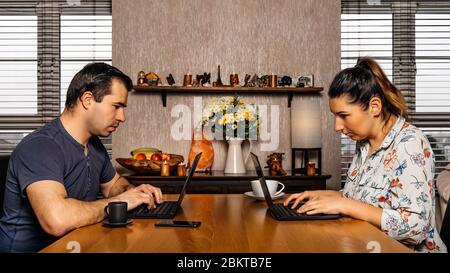 Men and woman, couple, working on computers from comfort of their home during covid 19 or coronavirus pandemics, lockdown and quarantine Stock Photo