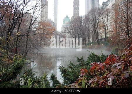 New York, America: 20/12/2019: Central Park, New Yorks largest park with lakes ponds and paths in mist with sky scrapers behind Stock Photo