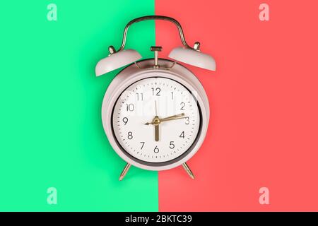 Ringing twin bell vintage classic alarm clock Isolated on red and green pastel colorful trendy background Stock Photo