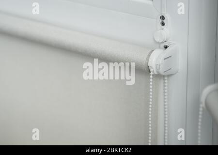 Details of white fabric roller blinds on the plastic window with wood texture in the living room. Stock Photo