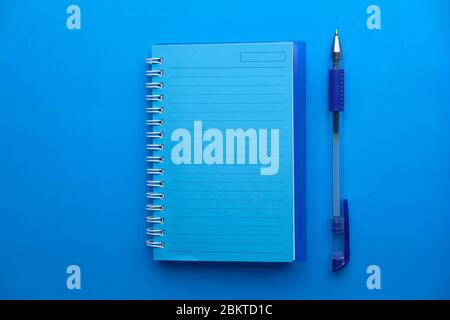 Top view of blue color notepad and pen on blue background  Stock Photo