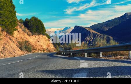 Picturesque empty winding country mountain road leading to Sierra Nevada snow capped ridge. Photo taken in Granada spanish city, ski resort. Sunny day Stock Photo