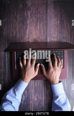 young man typing on laptop keyboard in office Stock Photo