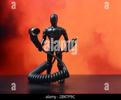 USB cable. USB cable, in the hands of Superman. Red background. USB cable on a red background. Plastic man Stock Photo