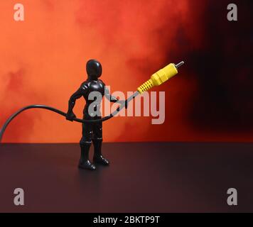 USB cable. USB cable, in the hands of Superman. Red background. USB cable on a red background. Plastic man Stock Photo