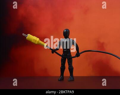 USB cable. USB cable, in the hands of Superman. Red background. USB cable on a red background. Plastic man Stock Photo