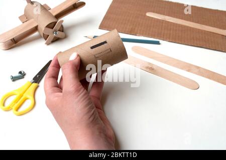 How to make airplane. Hand made toy,zero waste from toilet paper roll and popsicle sticks. For kids and parents. Step 3. Stock Photo