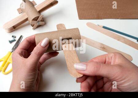 How to make airplane. Hand made toy,zero waste from toilet paper roll and popsicle sticks. For kids and parents. Step 4, first try wings. Stock Photo