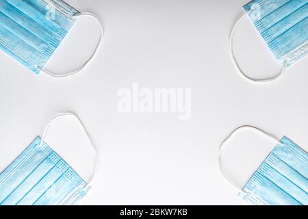 Several medical blue disposable protective masks lying one opposite the other on a white background. A surgical dressing closes the mouth and nose Stock Photo