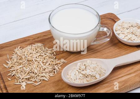Oatmeal milk with oat seeds on wooden background. Vegetarian food Stock Photo