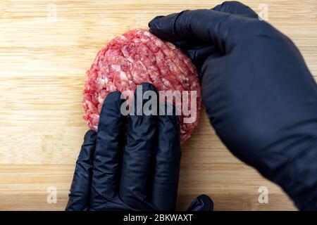 Raw beef burger cooking on natural bamboo wooden cutting board background close-up. Top view. Stock Photo