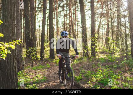 Cyclist wearing pollution mask. Young guy in respirator with filter pm 2.5 with ride on bike in park. Covid 19 Quarantine Sport. Mountain biker riding Stock Photo