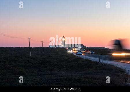 View of the Cabo de Sao Vicente lighthouse, located in the Sagres region, at sunset, with cars passing by on the road. Stock Photo