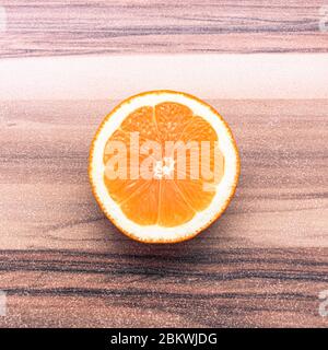 Symmetrical half of orange turned upward on a table with horizontal texture Stock Photo