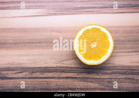 Single round lemon piece turned upward on a wooden table Stock Photo