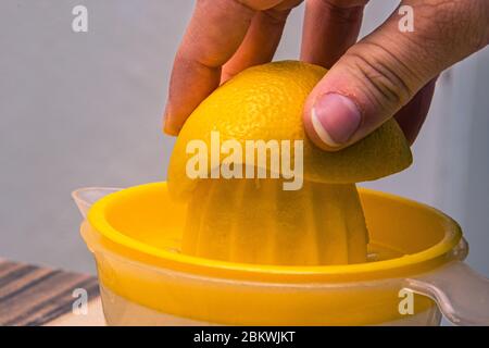 A half of yellow lemon squeezed on the plastic yellow juicer in the kitchen Stock Photo