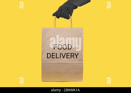 Delivery man hold craft paper packet with food isolated on yellow background. Service quarantine pandemic coronavirus virus 2019-ncov concept Stock Photo