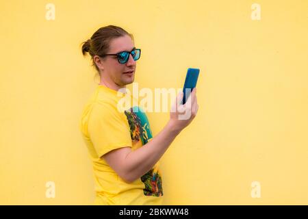 Portrait of smiling young man using his mobile phone isolated on yellow background Stock Photo