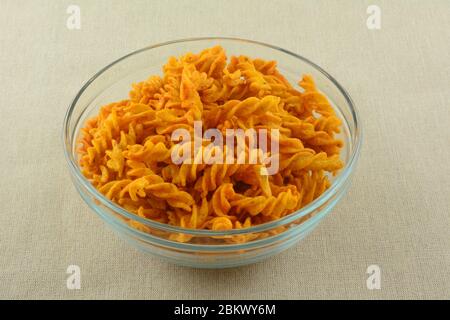 Snack of barbecue flavored corn snacks in twisted sticks in glass bowl Stock Photo