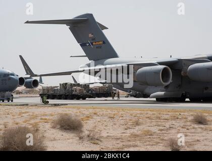 Airmen from the 386th Air Expeditionary Wing prepare to load cargo onto a C-17 Globemaster III, deployed assigned to Joint Base McGuire-Dix Lakehurst, N.J., at Ali Al Salem Air Base, Kuwait, May 2, 2020. The 386th AEW is U.S. Central Command’s theatre gateway and is responsible for delivering decisive combat power and unparalleled theatre support. (U.S. Air Force photo by Senior Airman Isaiah J. Soliz) Stock Photo