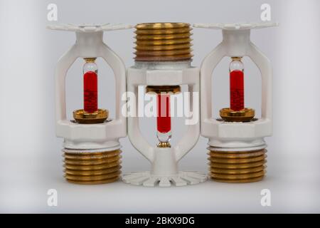 Close up image of fire sprinkler with fire in background. Fire sprinklers are part of an integrated water piping system designed for life and fire saf Stock Photo