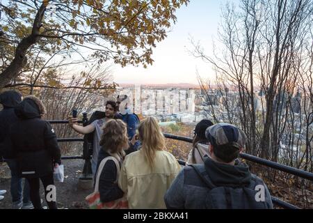 MONTREAL, NOVEMBER 4, 2018: Crowd of young tourists posing and taking selfies with a smartphone in front of an aerial landmark panorama of the busines Stock Photo
