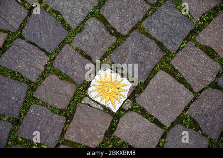 Close-up of a porphyry cubes street pavement in the old centre of Bardolino with a hand painted decoration representing a sun, Verona, Veneto, Italy Stock Photo