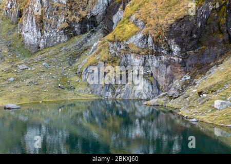 colorful rocky shore mirror reflection in calm Balea mountain lake Stock Photo