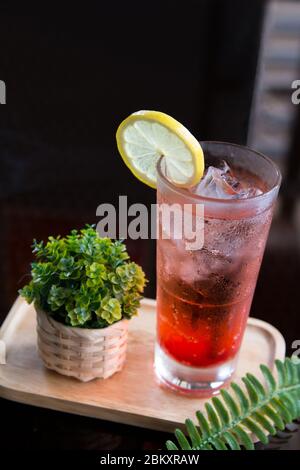 Homemade red cranberry lemonade with mini plant in a rattan basket on a wooden tray decoration. Stock Photo