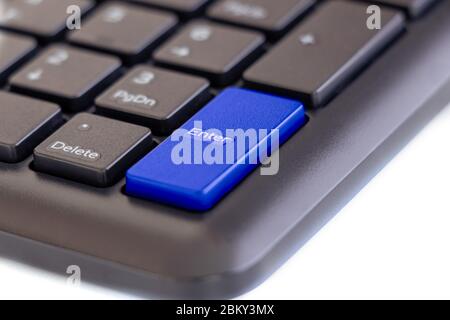 Enter key highlight with blue color on keyboard with finger pressing button on white background, selective focus Stock Photo