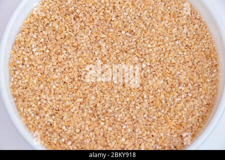 Bulgur (Daliya) in bowl, Bulgur wheat grains,  Raw cereal food, Dried cracked wheat. Stock Photo