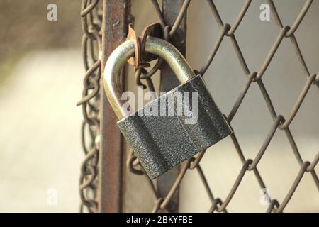 Gray iron shiny padlock hanging on an iron door in the street. Stock Photo