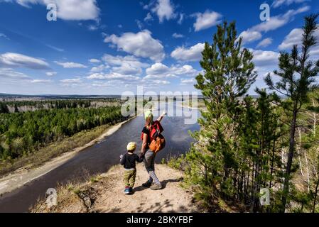 Vedenshina, Russia - April 29, 2020: Young mother shows her child a beautiful landscape in spring Irkut river with sky clouds. View from above Stock Photo