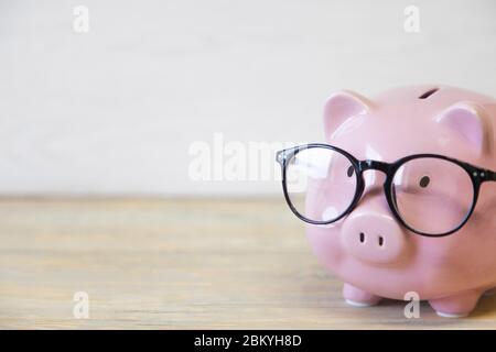 Piggy bank with glasses on the wooden background Stock Photo