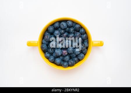 Vaccinium corymbosum. Blueberries in a yellow bowl on a white background Stock Photo