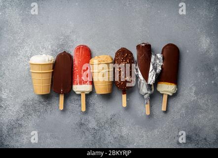 Chocolate ice cream popsicles and fruit ice cream with cones on gray cold stone background. Copy space for text. Stock Photo