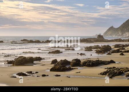 View of the Nugget point lighthouse in the distance from a rocky beach. Stock Photo