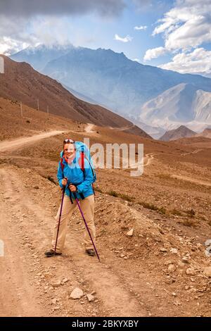 Young woman on mountain road in the background of mountain peaks in Lower Mustang, Nepal. Trekking in the Himalayas. Stock Photo