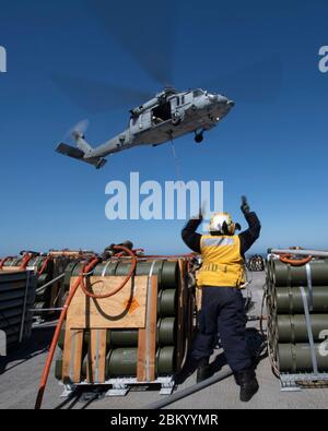 200505-N-IQ884-1625  PACIFIC OCEAN (May 5, 2020) Aviation Boatswain's Mate (Handling) Airman Felisity Natal, assigned to amphibious assault ship USS Boxer (LHD 4) signals the pilot of an MH-60S Seahawk attached to Helicopter Sea Combat Squadron (HSC) 21 as it lifts ordnance off the flight deck during an ammunition offload. Boxer is conducting routine operations in the eastern Pacific. (U.S. Navy photo by Mass Communication Specialist 2nd Class Dale M. Hopkins) Stock Photo