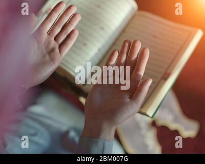 muslim man praying Allah alone inside the mosque and reading islamic holly book quran Stock Photo
