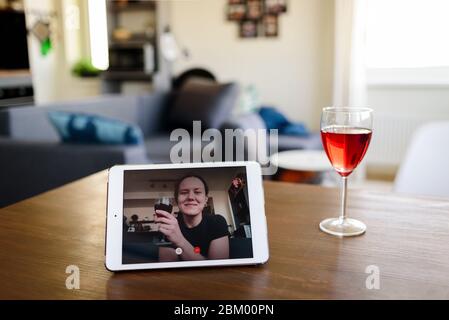 Man drinking red wine online with female friend using tablet pc at home Stock Photo