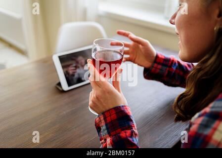 Woman drinking red wine online with male friend using tablet pc at home Stock Photo