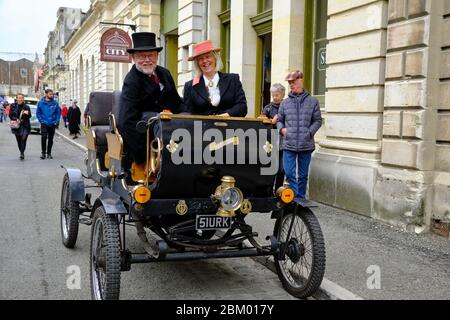 Senior couple traveling in a vintage Victorian car on the streets of Oamaru during a theme fair. Stock Photo