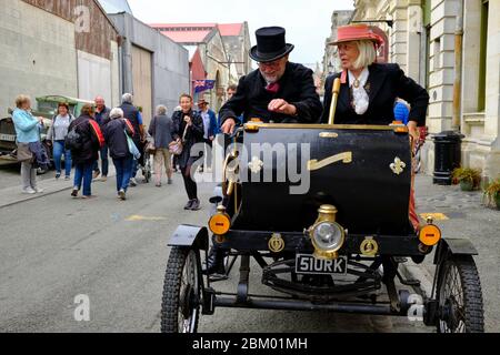 Senior couple traveling in a vintage Victorian car on the streets of Oamaru during a theme fair. Stock Photo