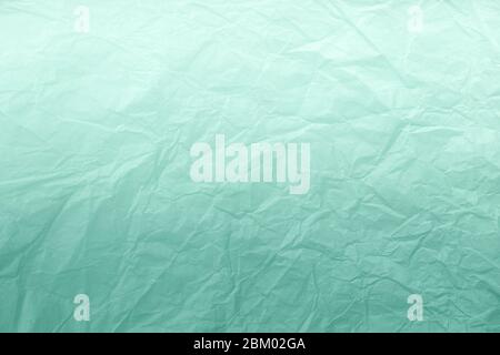 Texture of crumpled green wrapping paper with white gradient, closeup. Light cyan old background. Material mint backdrop. Stock Photo